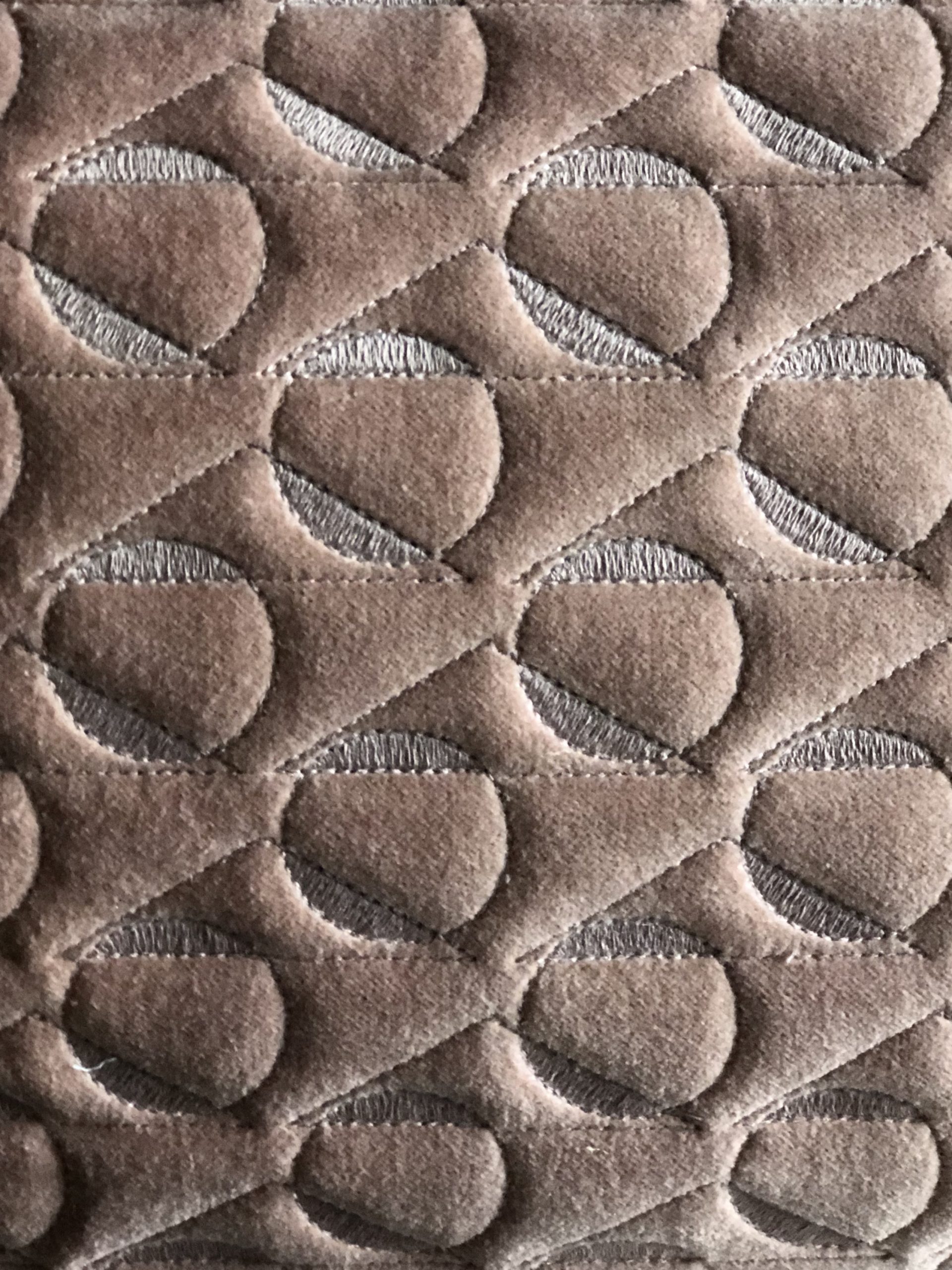Tight details of dusky pink velvet with stitched geometric design.